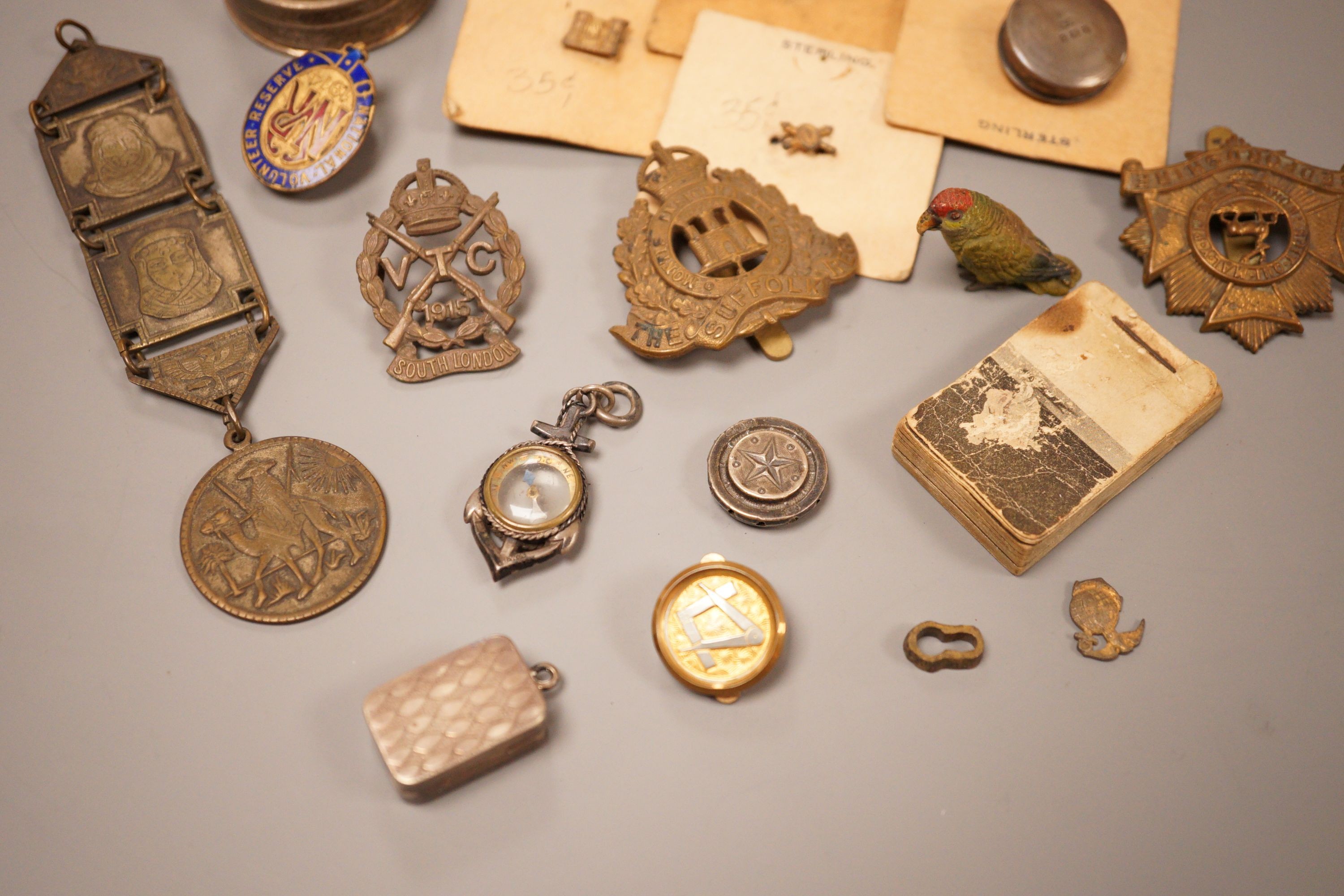 A selection of various miscellaneous items, to include a George III silver vinaigrette, a military pin badge, an Edwardian flick book, a cold painted parrot, and others.